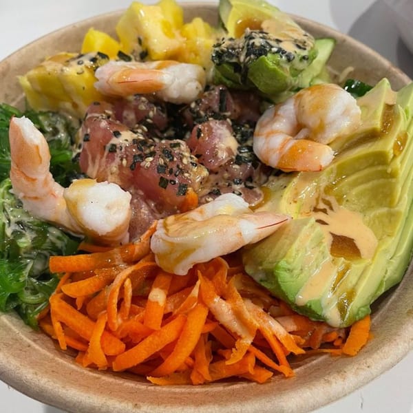 Close-up of a Poke Mahi bowl with tuna, shrimp, avocado, mango, seaweed, and carrots.