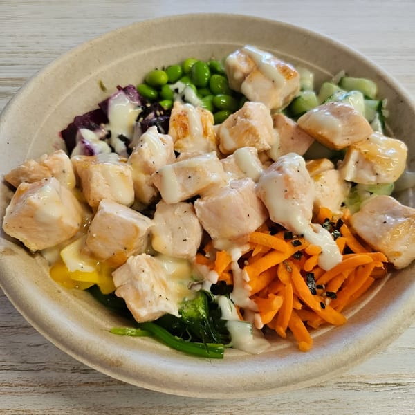 Close-up of a Poke Mahi poke bowl with chicken, edamame, carrots, and other fresh ingredients.
