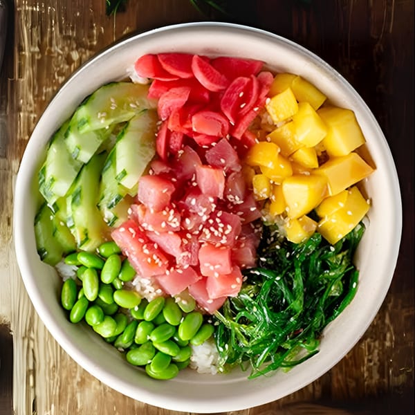 Colorful poke bowl with tuna, mango, cucumber, edamame, seaweed, and pickled radishes.